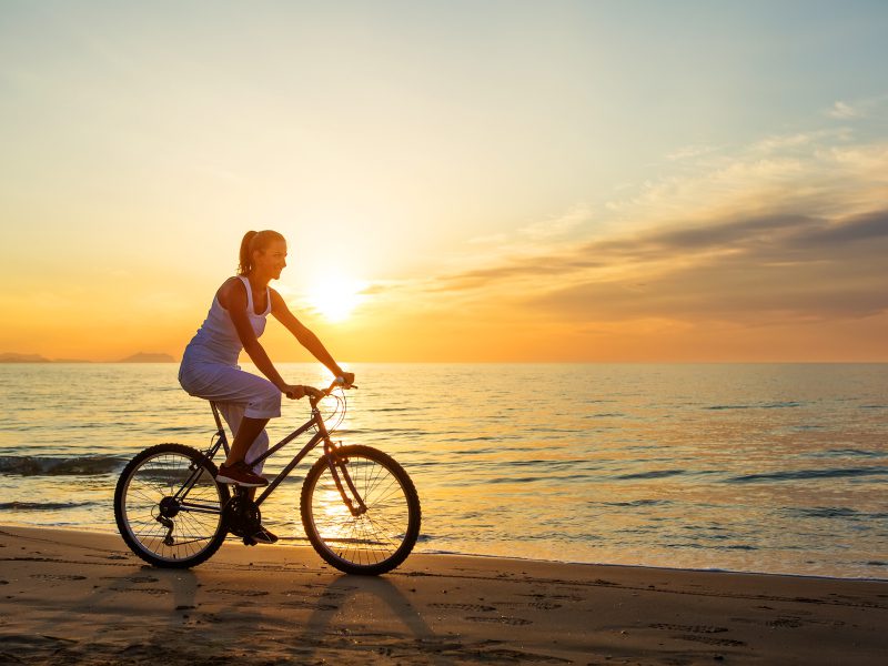 A woman rides a bicycle on a Maldivian beach